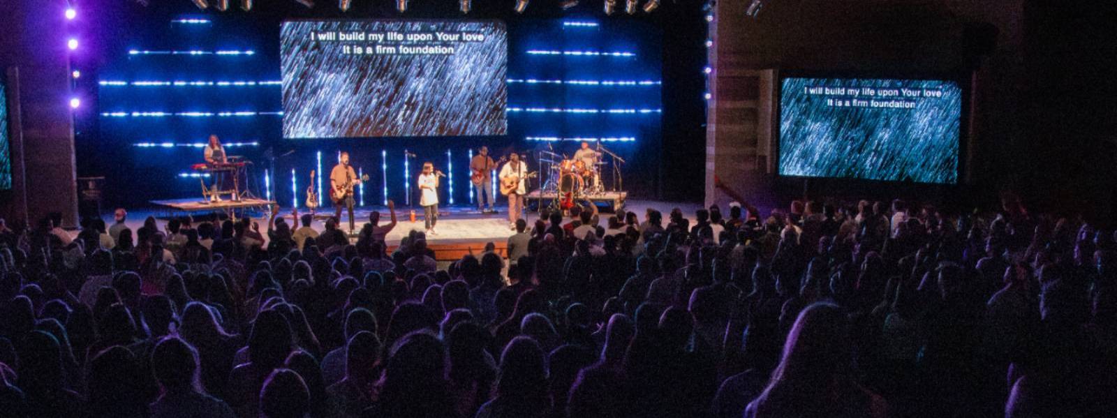 three guitarists and drummer leading worship in chapel service