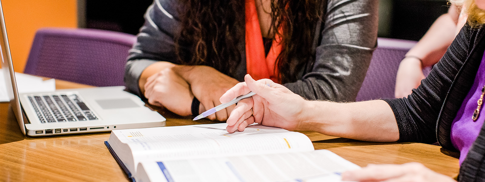 accounting professor looks at computer with student to help her with homework assignment